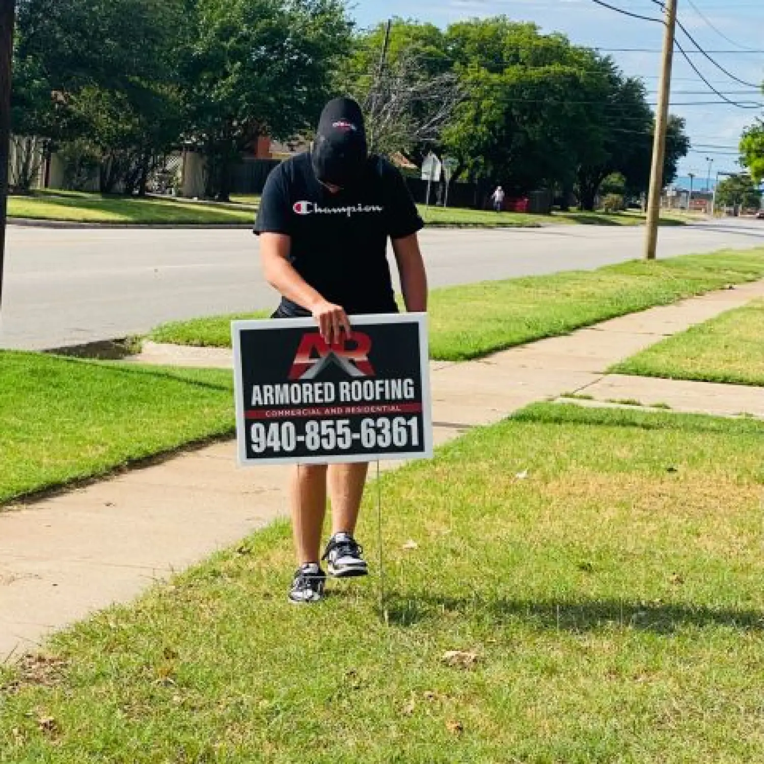 Man installing Armored Roofing yard sign.
